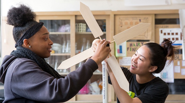 Two school students designing a wind turbine prototype in wood.