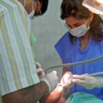 Two dentists performing a procedure on a patient in a clinic.
