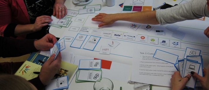 Students (faces not seen) are sitting around a table working with flash cards and stickers.